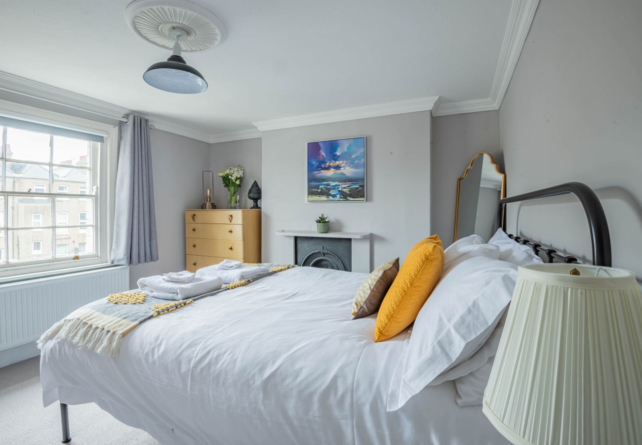 Light king bedroom with ochre cushions